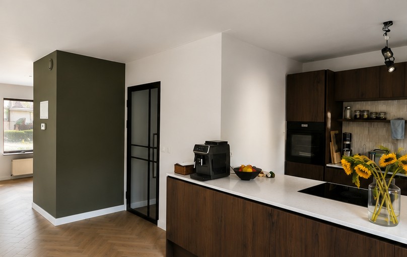 Open keuken en woonkamer met strak gesausde witte wanden en een olijfgroene accentwand